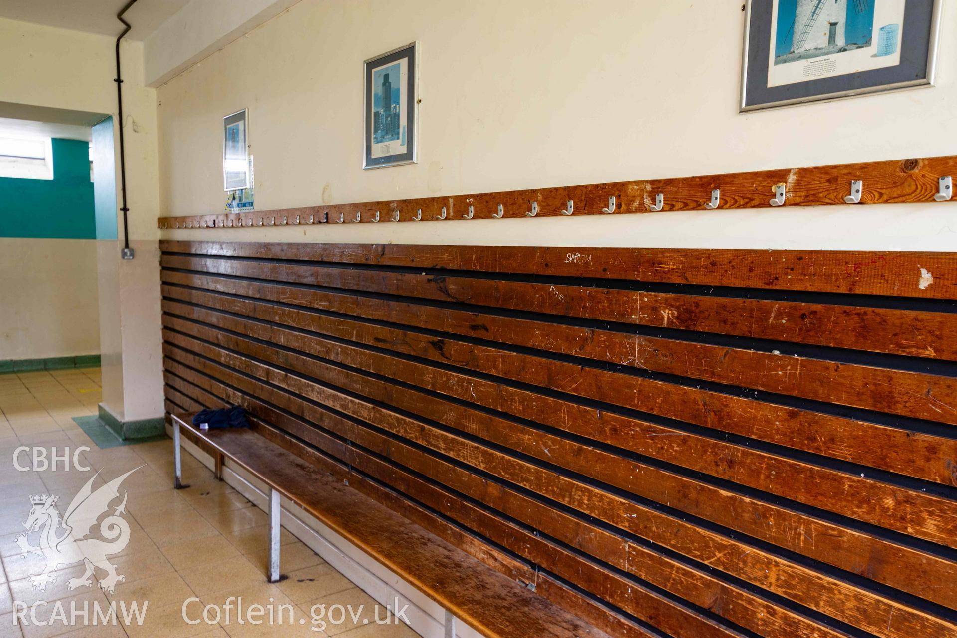Wooden bench and pannelled back with clothes hooks above, north central range