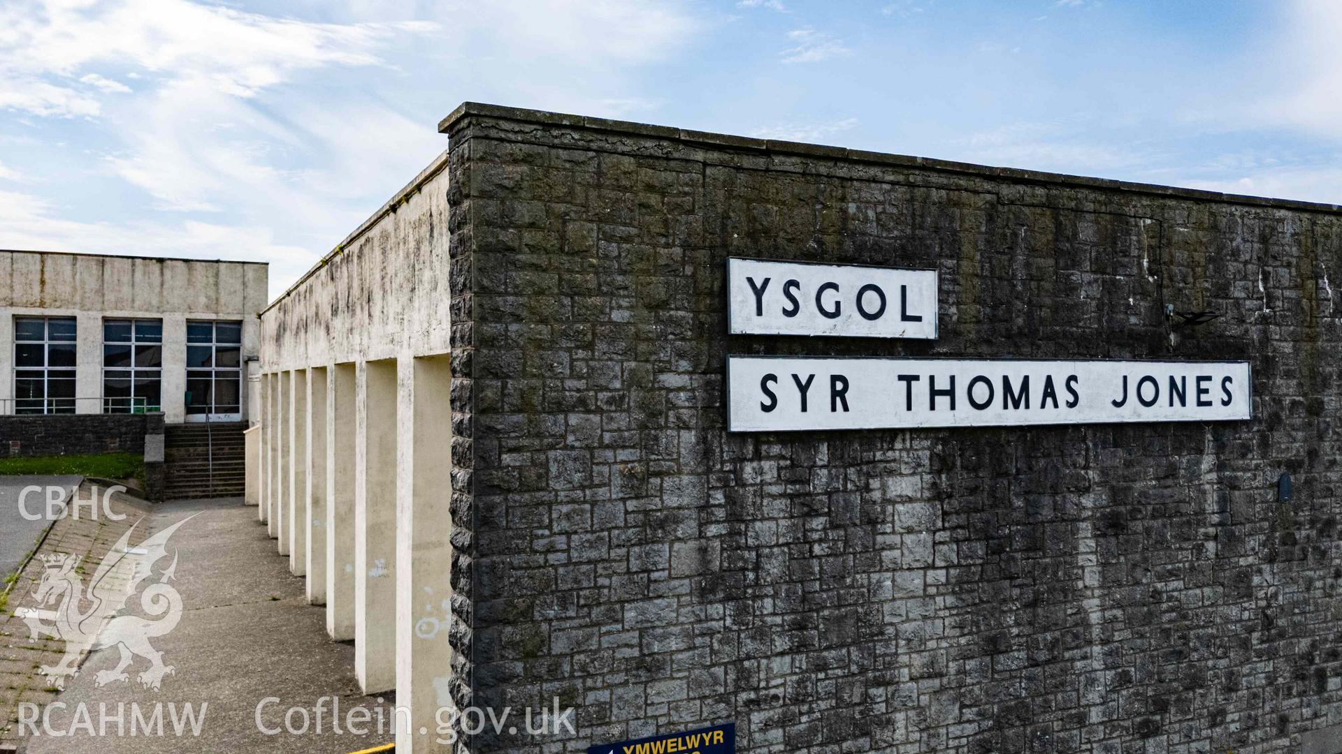 Angled aerial photo of 'Ysgol Syr Thomas Jones' signage on east elevation of boys' gymnasium. View also along south elevation