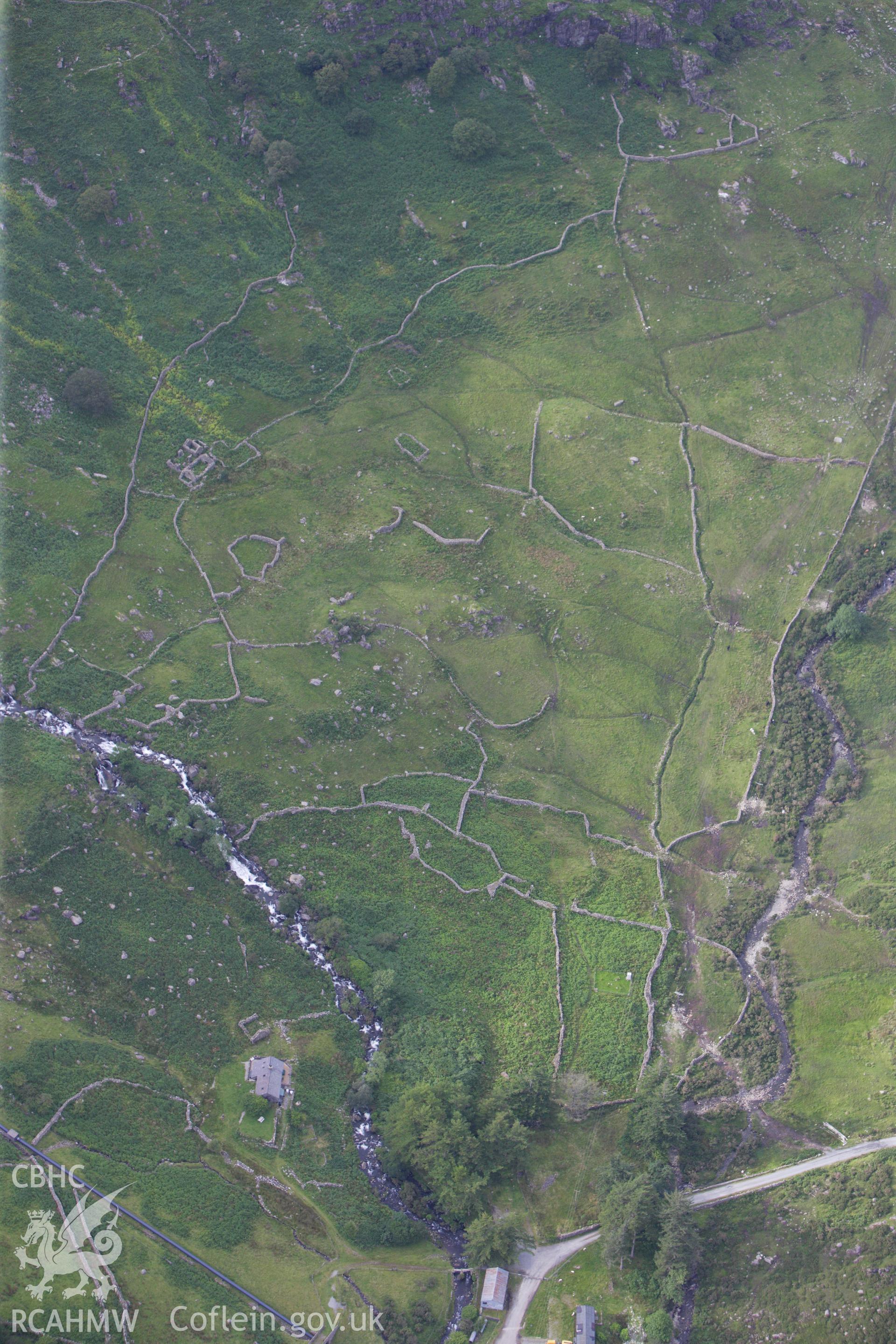 RCAHMW colour oblique aerial photograph of a hut circle settlement north of Cwm Dyli Power Station. Taken on 06 August 2009 by Toby Driver