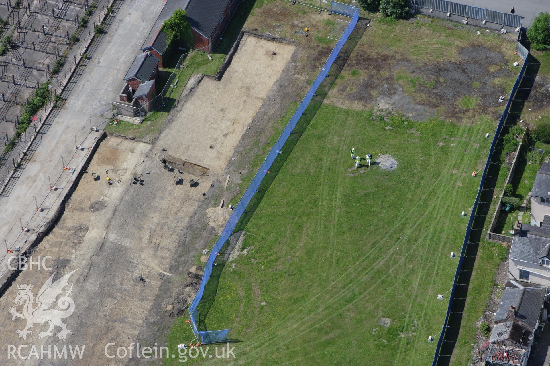 RCAHMW colour oblique aerial photograph of the Roman road in a field adjacent to the Smithfield Market in Newtown showing excavations by the Clwyd-Powys Archaeological Trust on the Tescos site. Taken on 02 June 2009 by Toby Driver