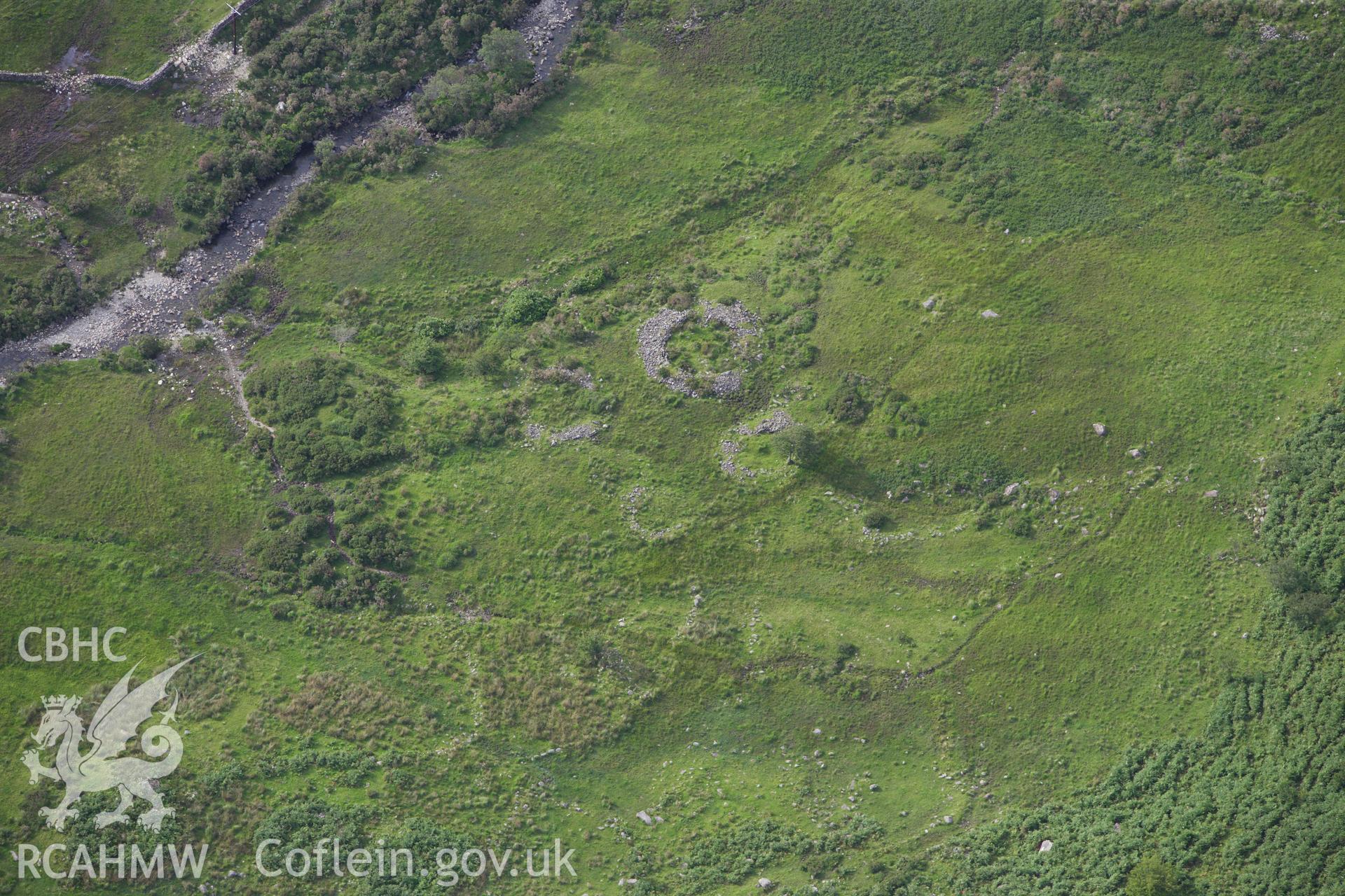 RCAHMW colour oblique aerial photograph of a hut circle settlement north of Cwm Dyli Power Station. Taken on 06 August 2009 by Toby Driver