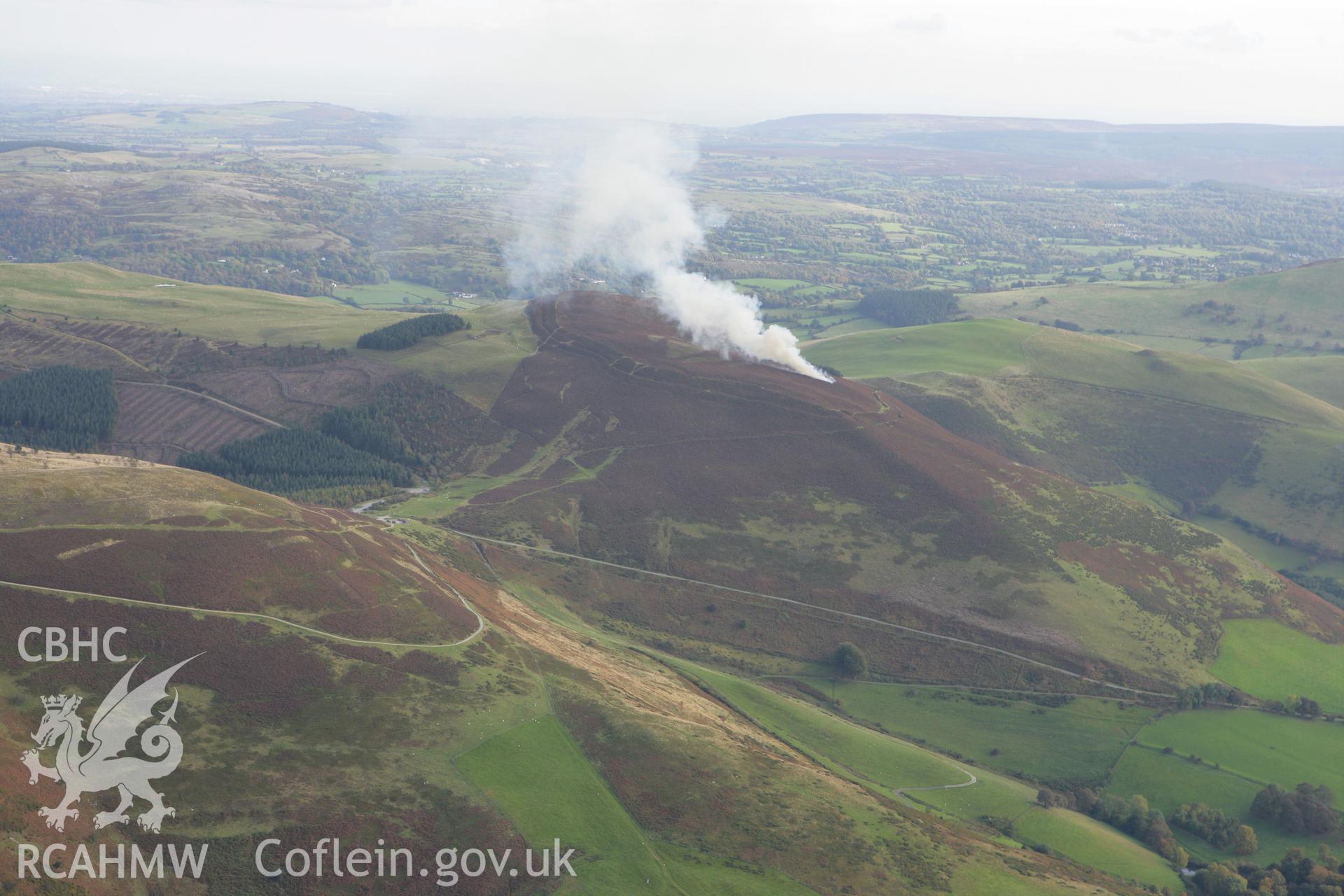 RCAHMW colour oblique aerial photograph of Foel Fenlli Hillfort showing a controlled heather burn. Taken on 13 October 2009 by Toby Driver