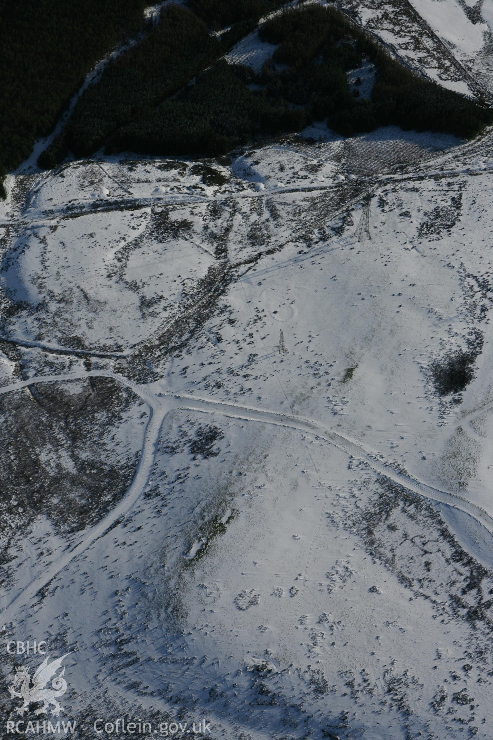 RCAHMW colour oblique photograph of Bryn Llechwedd cairn, and prehistoric enclosures. Taken by Toby Driver on 06/02/2009.