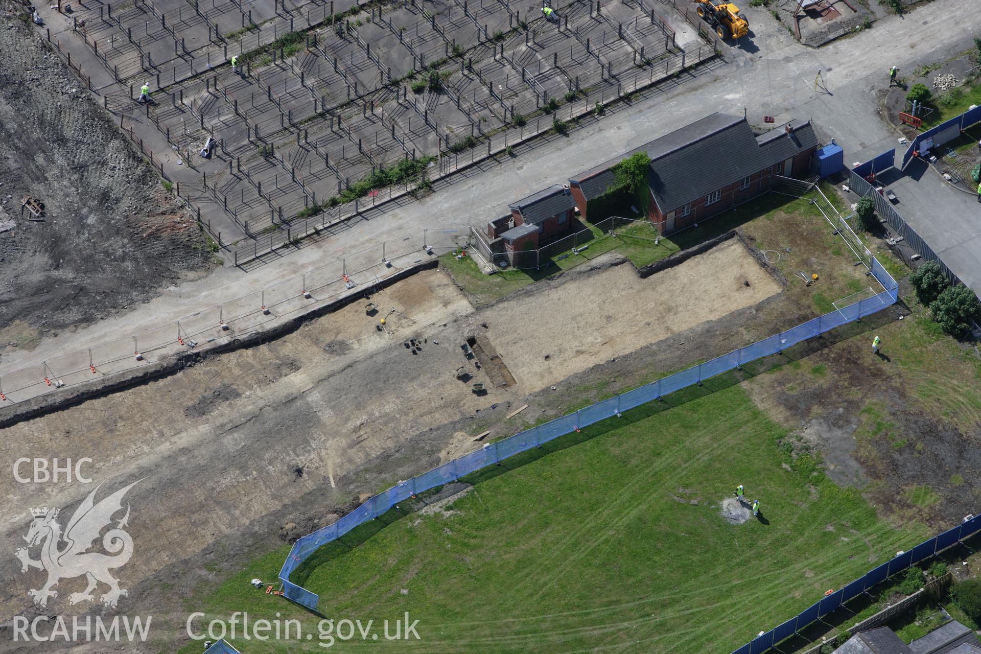 RCAHMW colour oblique aerial photograph of the Roman road in a field adjacent to the Smithfield Market in Newtown showing excavations by the Clwyd-Powys Archaeological Trust on the Tescos site. Taken on 02 June 2009 by Toby Driver