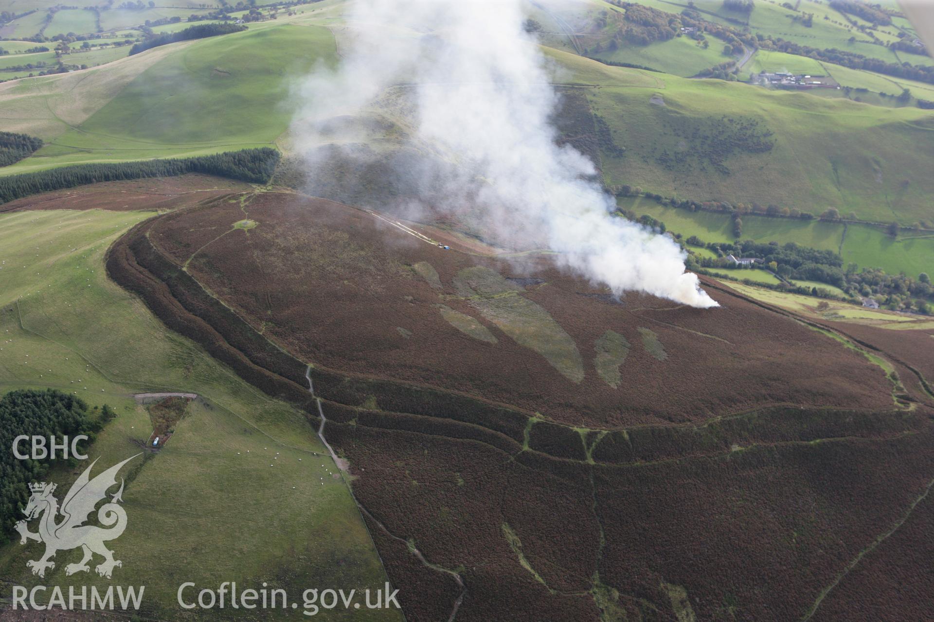 RCAHMW colour oblique aerial photograph of Foel Fenlli Hillfort showing a controlled heather burn. Taken on 13 October 2009 by Toby Driver