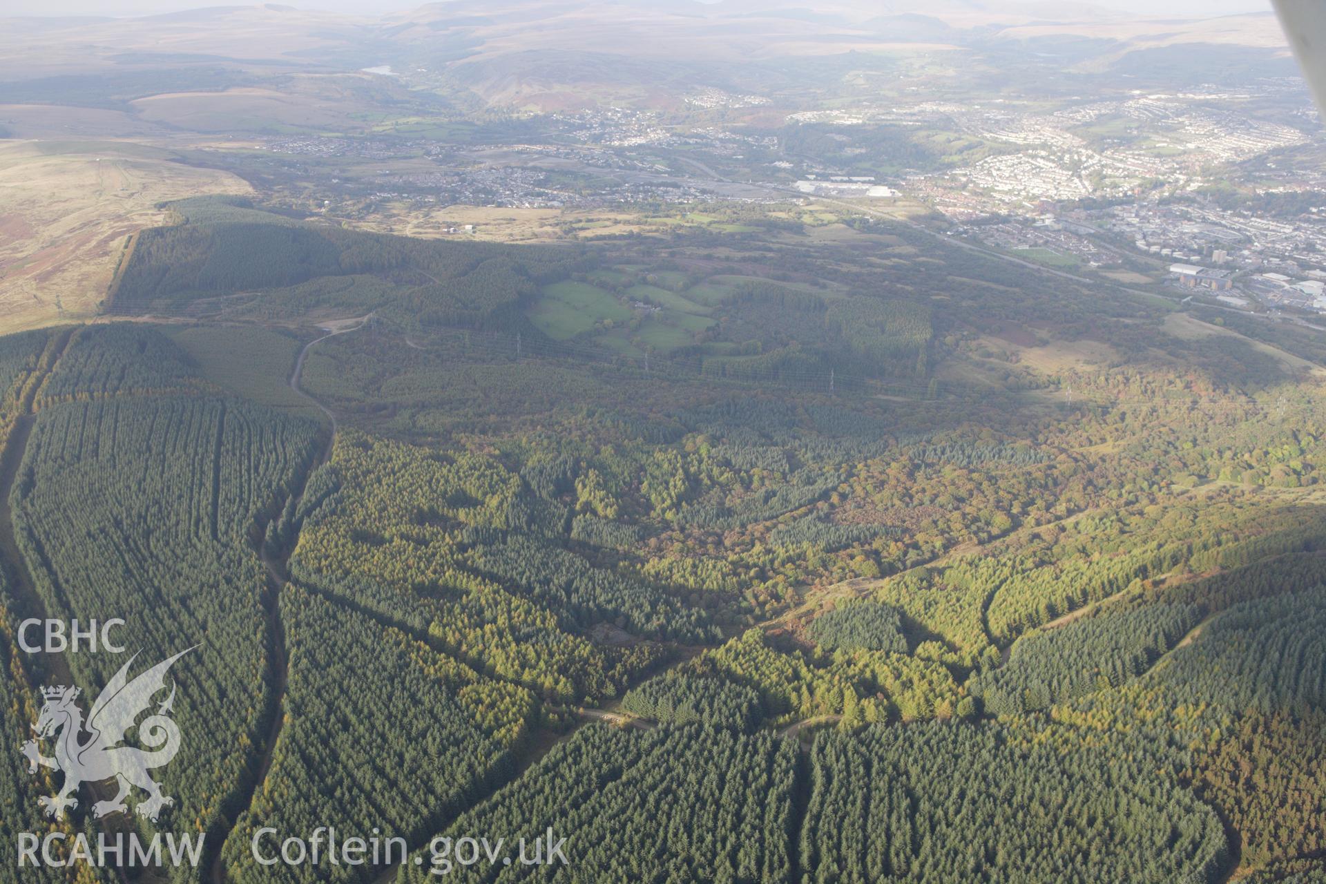 RCAHMW colour oblique aerial photograph of forestry north-east of Aberdare with Cwm Pit Colliery at Abercanaid visible in the distance. Taken on 14 October 2009 by Toby Driver