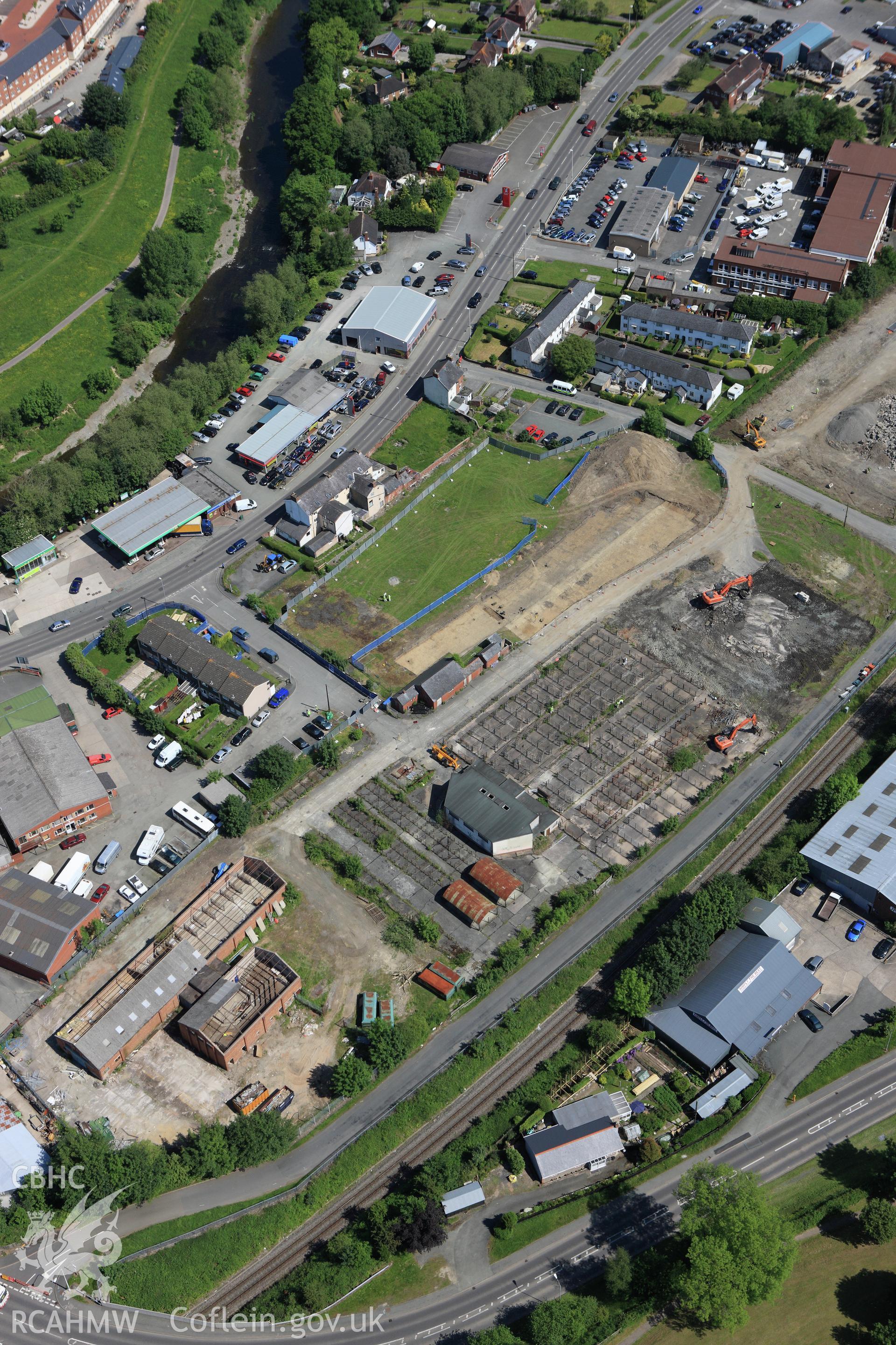 RCAHMW colour oblique aerial photograph of the Roman road in a field adjacent to the Smithfield Market in Newtown showing excavations by the Clwyd-Powys Archaeological Trust on the Tescos site. Taken on 02 June 2009 by Toby Driver