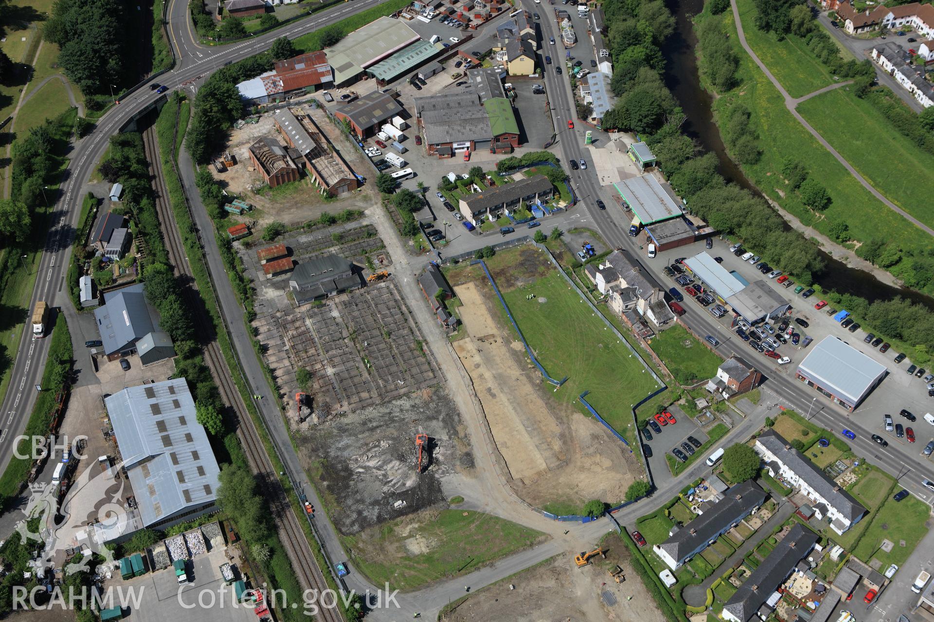 RCAHMW colour oblique aerial photograph of the Roman road in a field adjacent to the Smithfield Market in Newtown showing excavations by the Clwyd-Powys Archaeological Trust on the Tescos site. Taken on 02 June 2009 by Toby Driver