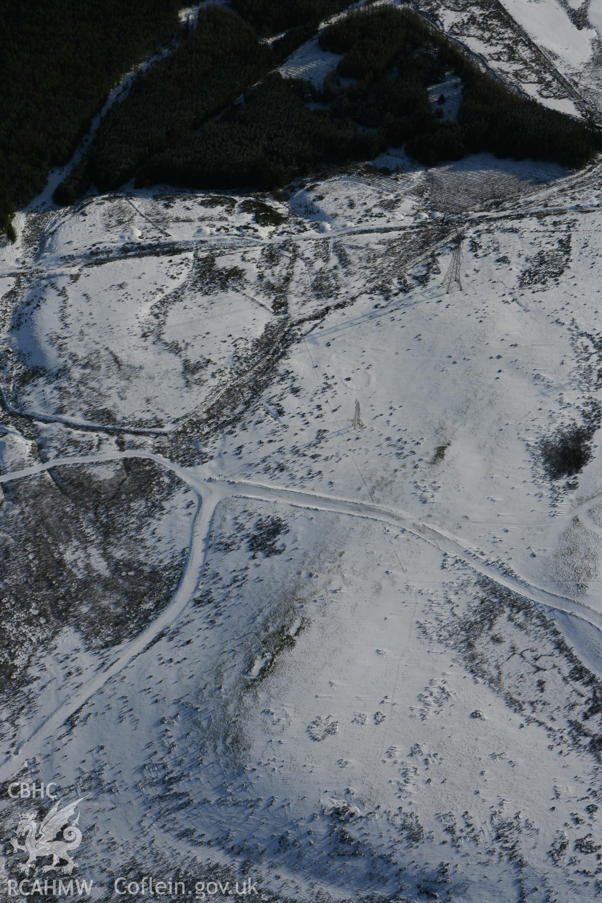 RCAHMW colour oblique photograph of Bryn Llechwedd cairn, and prehistoric enclosures. Taken by Toby Driver on 06/02/2009.