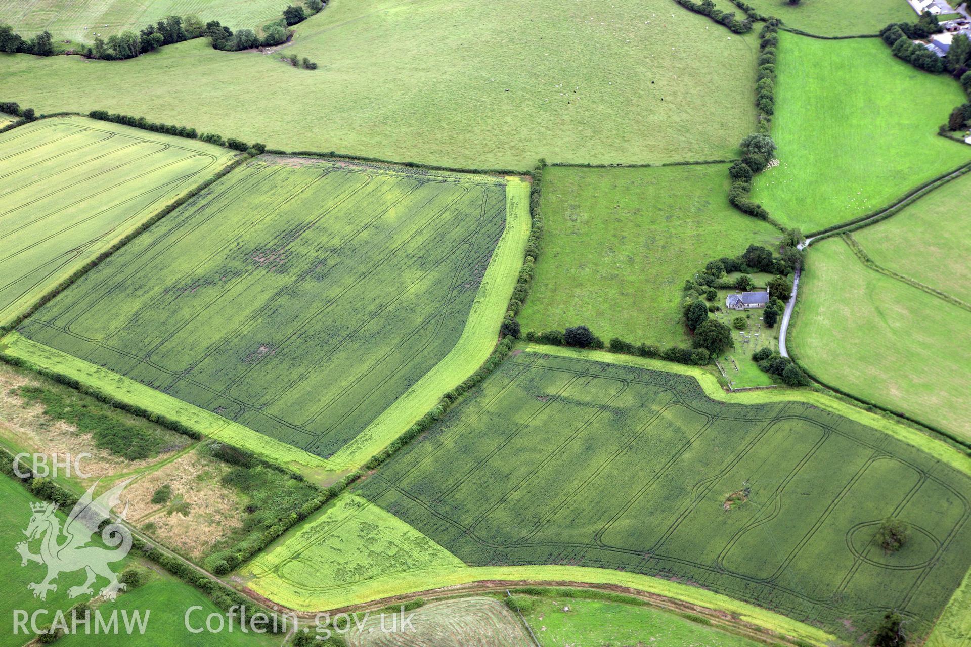 RCAHMW colour oblique aerial photograph of Langstone Church, Langstone, showing natural cropmarks of former pond or quarry. Taken on 09 July 2009 by Toby Driver
