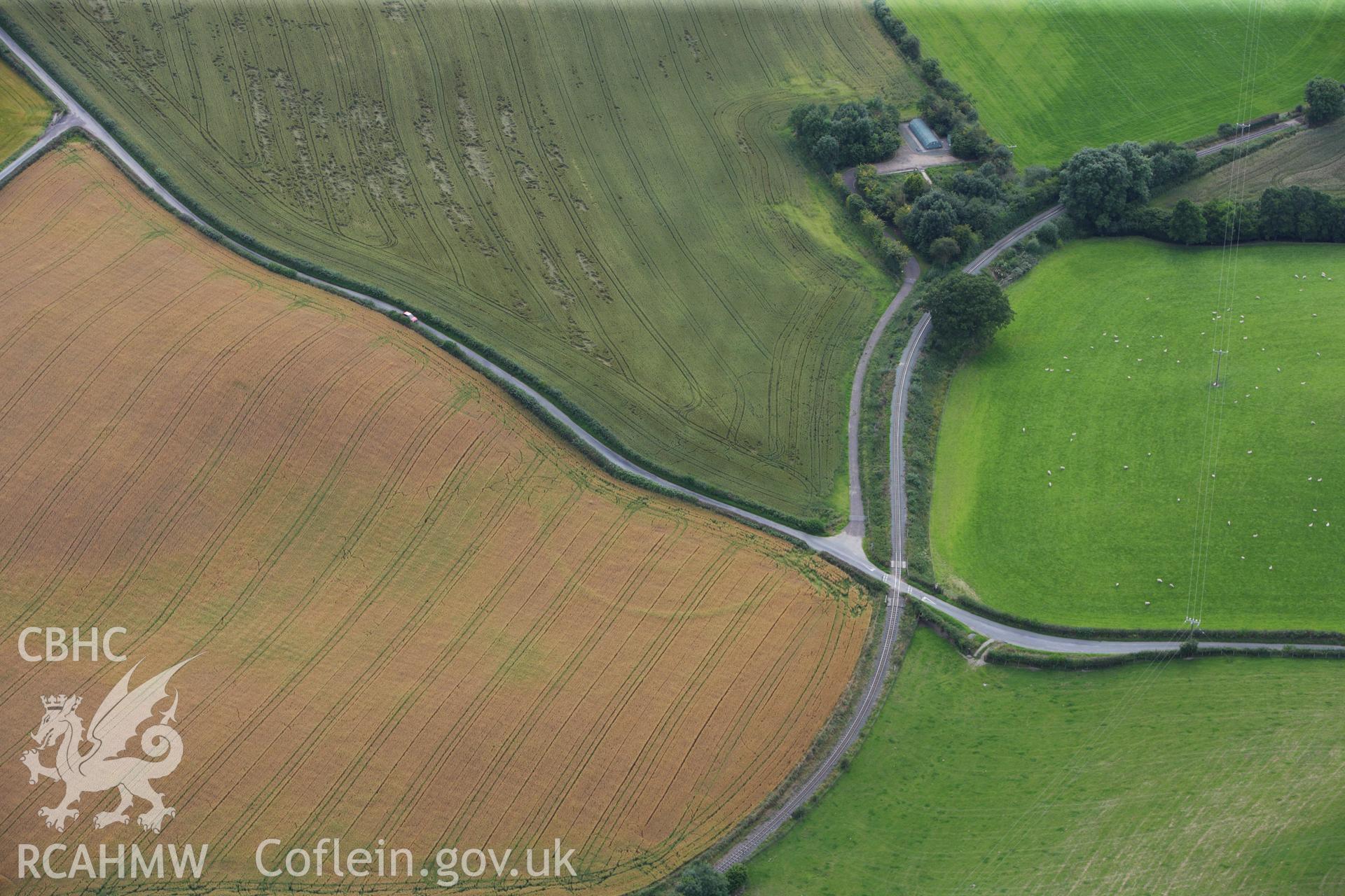 RCAHMW colour oblique aerial photograph of a cropmark enclosure at Cwm, northeast  of Castle Caereinion. Taken on 06 August 2009 by Toby Driver