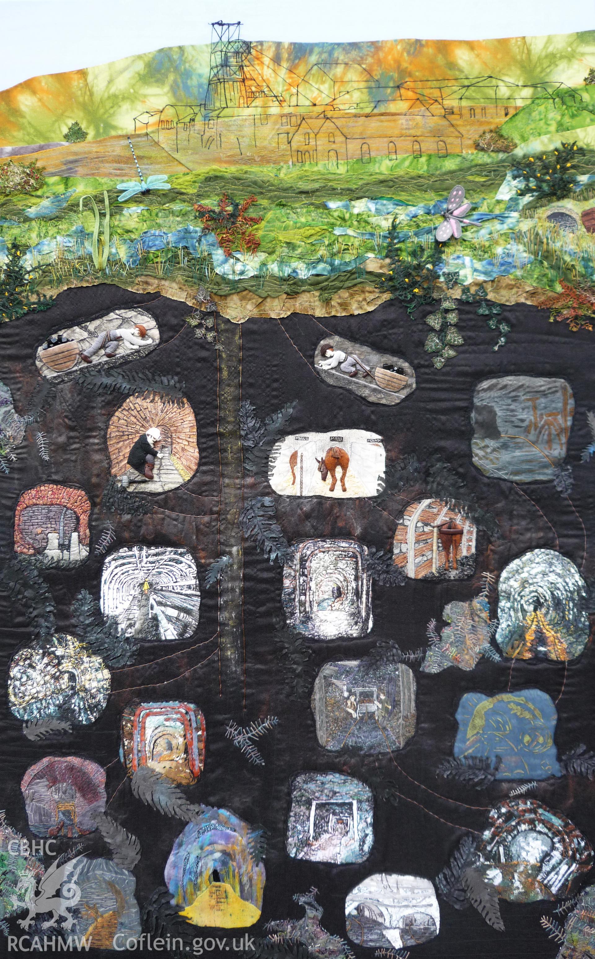 Digital image showing wall hanging entitled 'Big Pit'. Created by The Mad Mountain Stitchers. Measuring 128cm long by 80cm wide, the textile combines various techniques (including applique, reverse applique, stumpwork, embellishing, needlelace, stencilling, and hand and machine embroidery) applied to many different material types (felt, organza, calico, cottons, dyed and painted leather, beads silk tops, voiles, and various dyed and variagated threads).