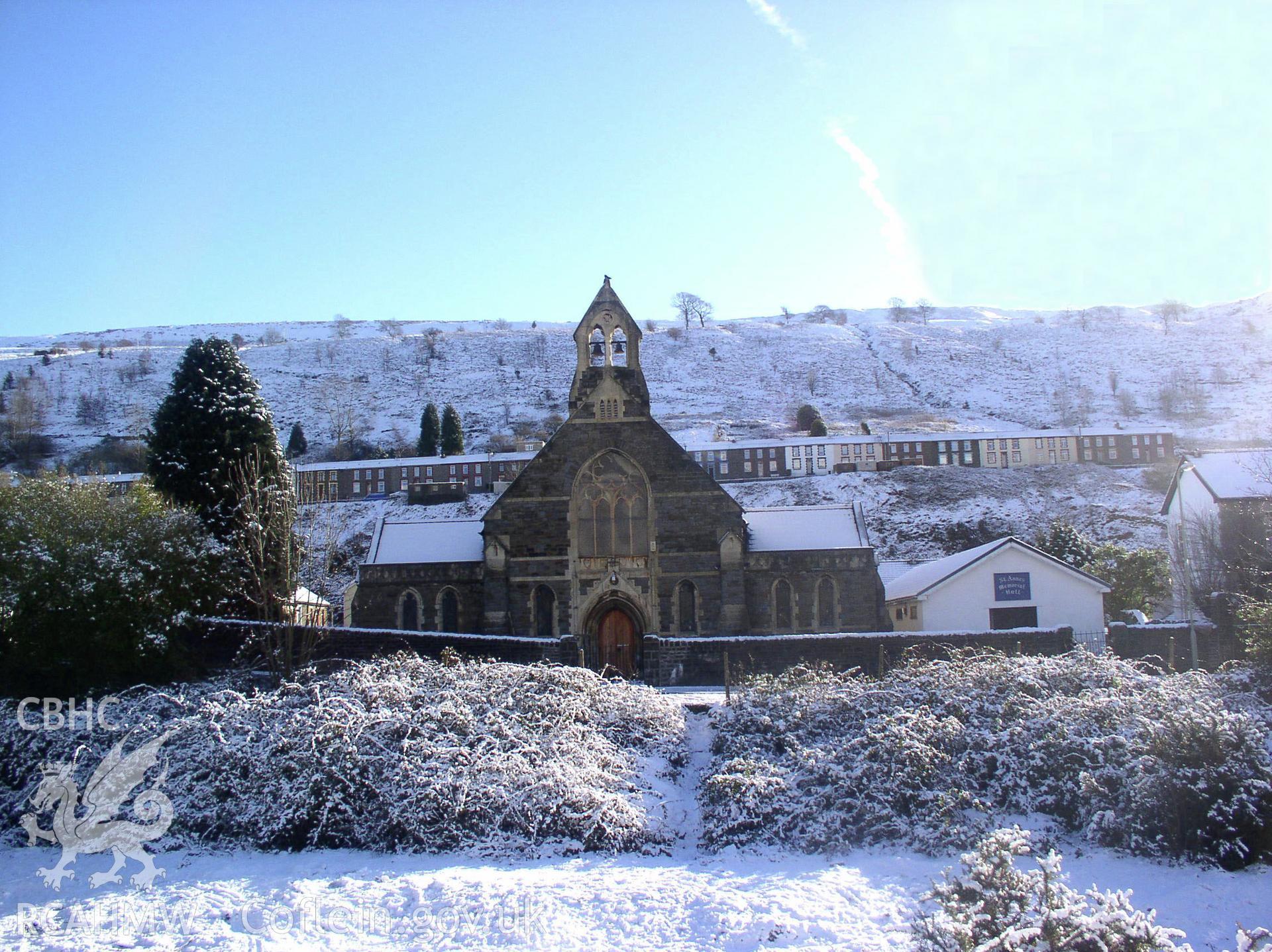 Colour digital photograph showing an elevation view of St Anne's Church, Ynyshir; Glamorgan. The photograph shows the church covered in the snow.